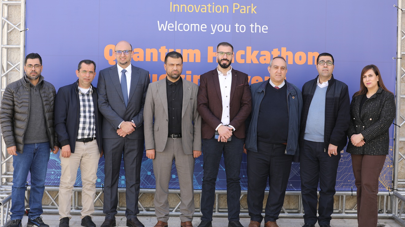 Event organizers gather in front of the Quantum Hackathon banner at An-Najah National University.